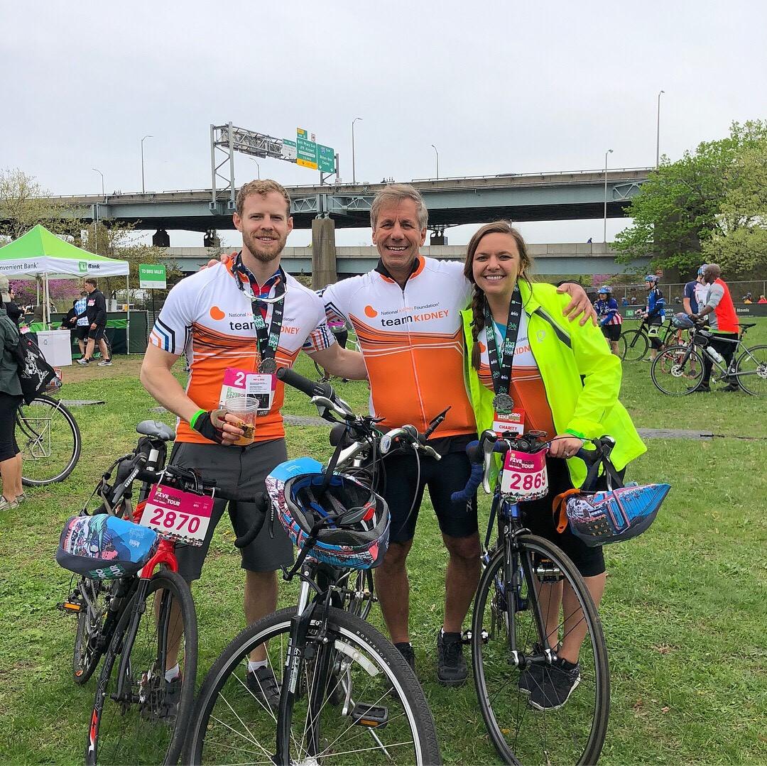 Three people posing for a picture in front of their bicycles
